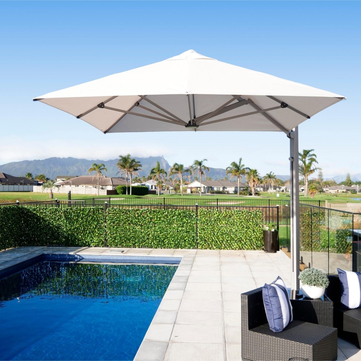 Shadowspec Serenity Rotating Cantilever Umbrella at a residential poolside with palm trees in background