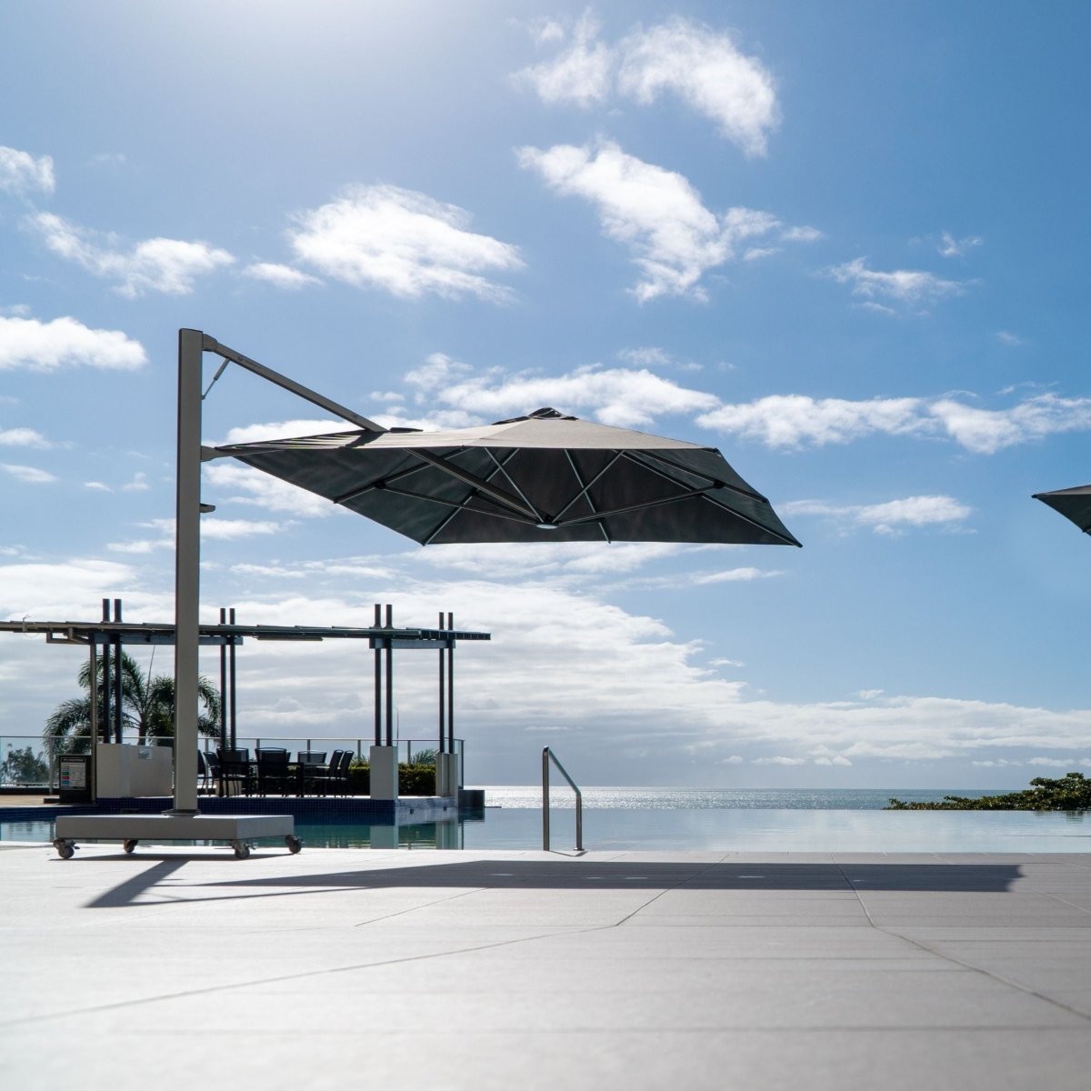 Shadowspec Serenity Rotating Cantilever Umbrella at a resort poolside with ocean view in the background