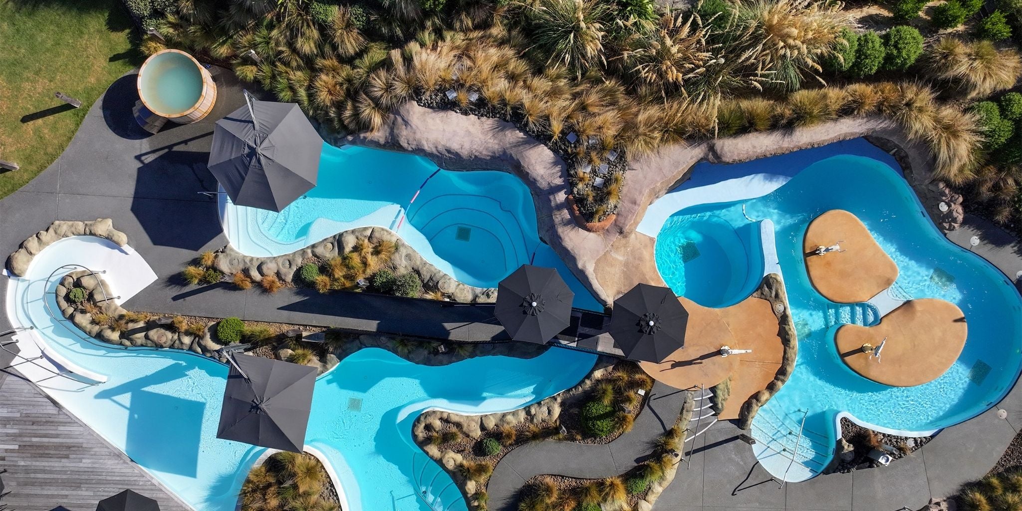 Arial view of Shadowspec Serenity and Oasis umbrellas at a resort poolside with plants