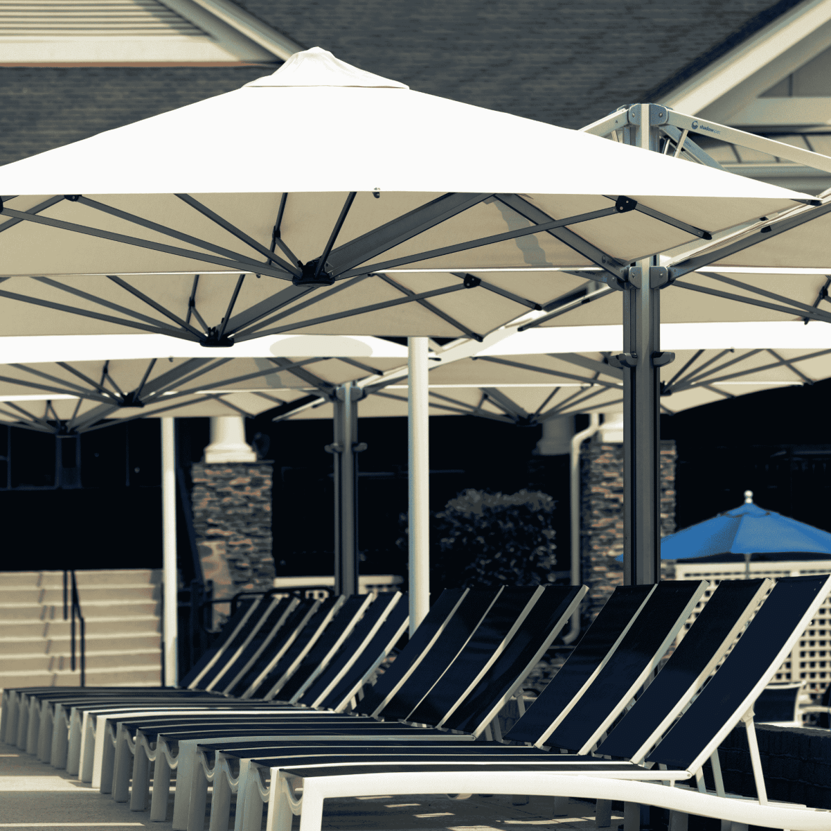 Shadowspec Unity Quattro Multi-Canopy Cantilever umbrella at a resort pool side