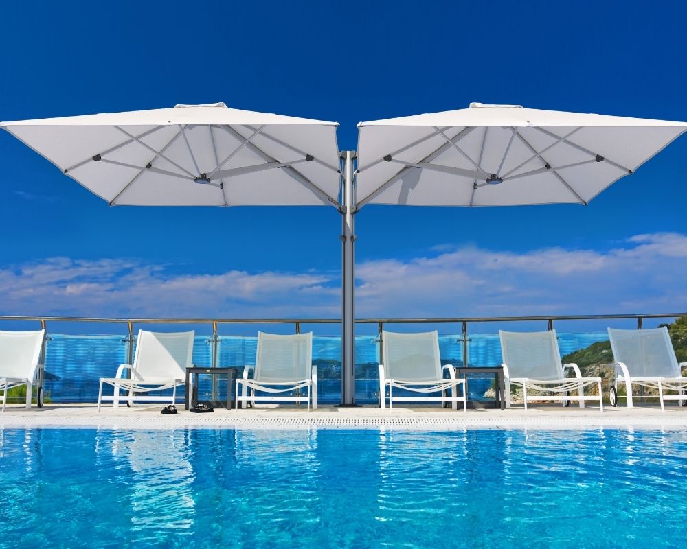 Shadowspec Unity Duo umbrella at a luxurious poolside with a blue sky