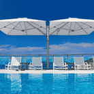 Shadowspec Unity Duo Multi-Canopy Cantilever umbrella at a poolside with clear blue sky in background